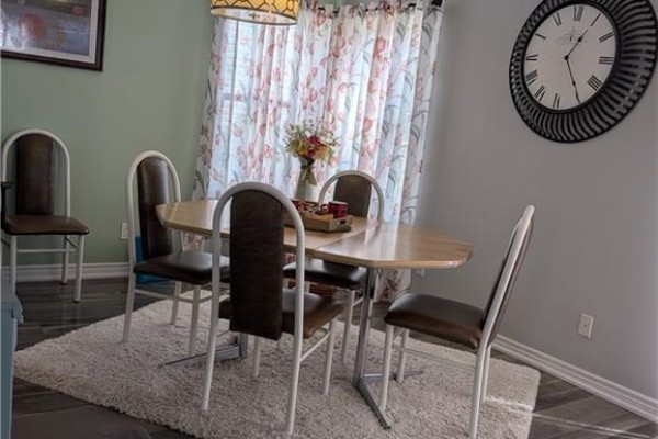 Dining room with oval table, chairs, rug, clock, and floral curtains - 62 Ninth Avenue Brantford