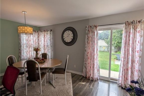 Oval dining table and chairs with large clock and backyard view - 62 Ninth Avenue Brantford