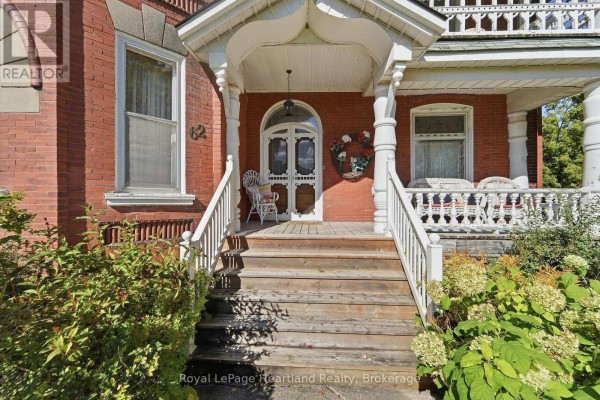 Close-up of a wooden staircase leading to a white-paneled front door with glass. - 62 Orange Street S, Central Huron