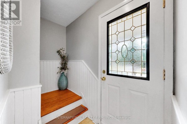 View of the front door and staircase with wood steps and white wainscoting. - 62 Porchester Drive, Toronto