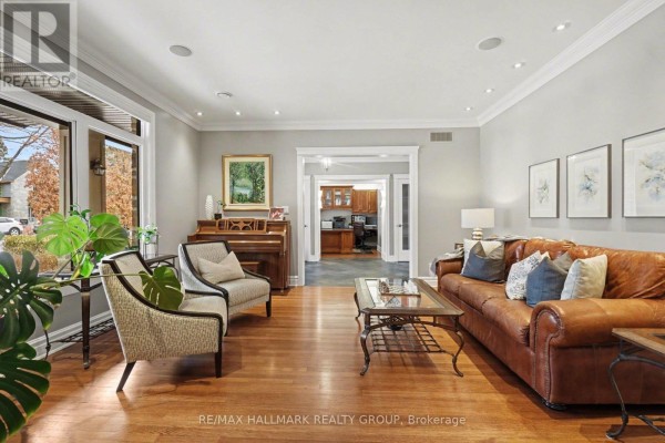 Living room with leather sofa, coffee table, piano, and hardwood floors. - 62 Rebecca Crescent, Ottawa
