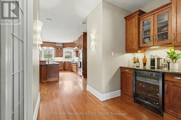 Kitchen and wet bar area with wood cabinets, granite countertops, and wine fridge. - 62 Rebecca Crescent, Ottawa