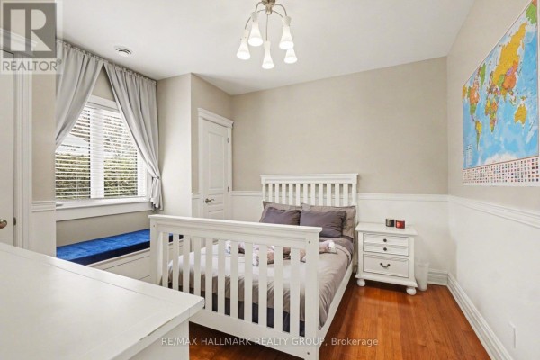 Bedroom with white crib, nightstand, window seat, and world map on wall. - 62 Rebecca Crescent, Ottawa