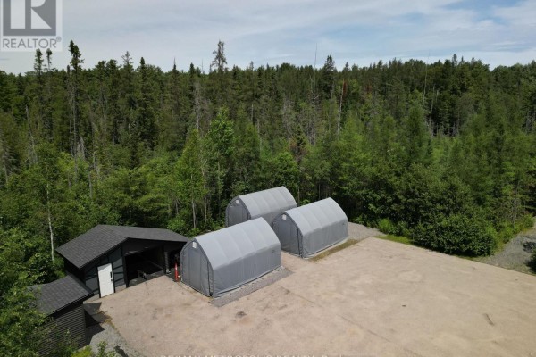 Three grey hoop buildings situated on a gravel pad next to a dark shed. - 62 South Mary Lake Road S, Huntsville