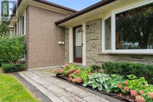 Close-up of the front entrance with a paved walkway and flowering plants. - 62 Summerside Crescent, Toronto