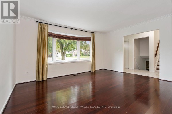 Living room with dark hardwood floors, white walls, and a large bay window. - 62 Summerside Crescent, Toronto
