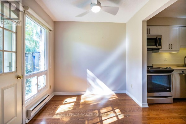 Dining area adjacent to a kitchen, with hardwood floors and a glass door. - 62 Thorny Vineway, Toronto