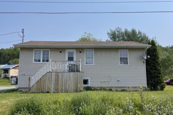 The side exterior of the beige vinyl-sided house with a wooden deck and stairs. - 62 Timmons Maclean Road, Newtown