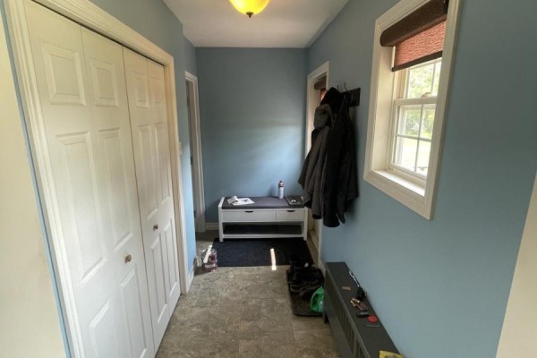 The home's hallway with light blue walls, white double doors, and a white storage bench. - 62 Timmons Maclean Road, Newtown
