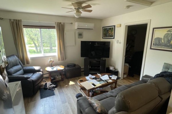 The living room with leather sofas, a coffee table, a television, and wood-look flooring. - 62 Timmons Maclean Road, Newtown