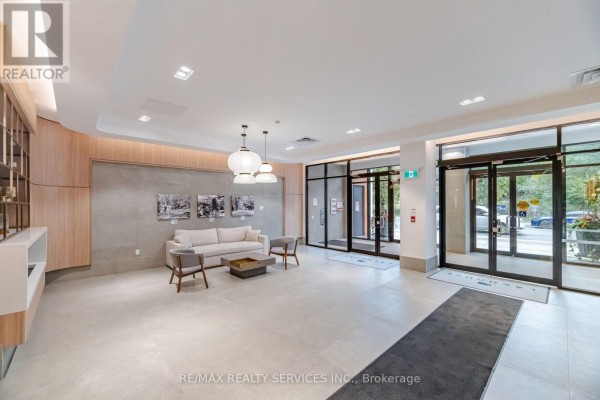 Apartment building lobby with light beige floor tiles, grey sofa, chairs, and modern pendant lights. - 620 - 185 Dunlop Street E, Barrie