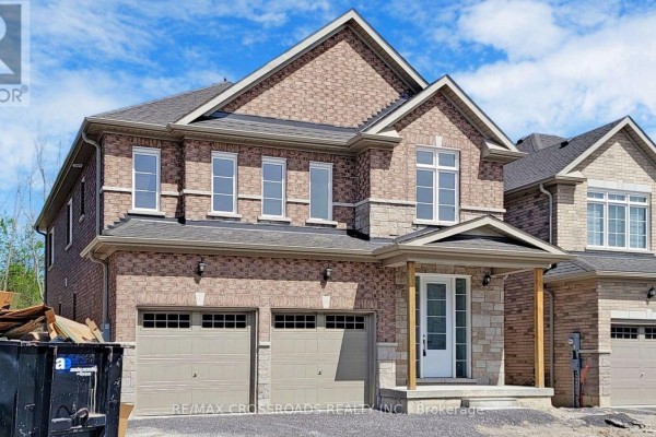 Exterior of a beige brick house with a peaked roof and double garage. - 620 Lemay Grove, Peterborough