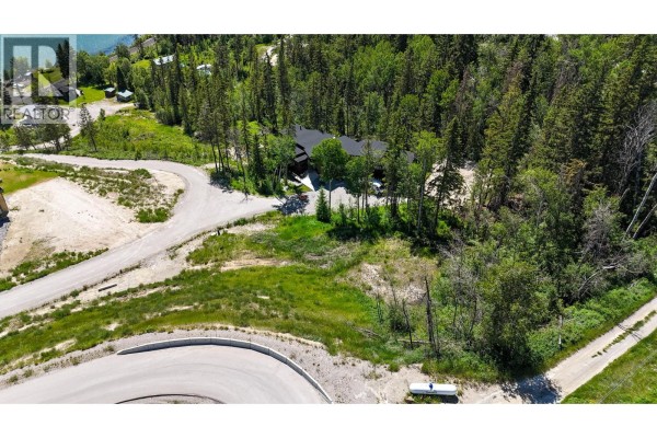 Aerial view of wooded lot with curved road and distant lake. - 6200 Columbia Lake Road Road Lot# 2, Fairmont Hot Springs