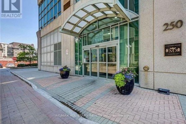 Building lobby with blue wave wall art, two dark chairs, and plants. - 621 - 250 Manitoba Street, Toronto