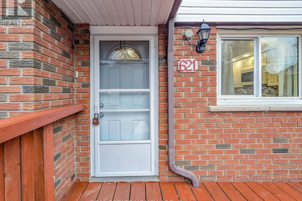 Front entrance of a brick house with a white screen door, address number 621, and a window. - 621 Byron Street S, Whitby