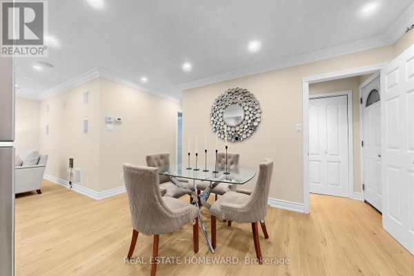 Dining area with a glass table, four upholstered chairs, and a decorative mirror on a cream wall. - 621 Byron Street S, Whitby