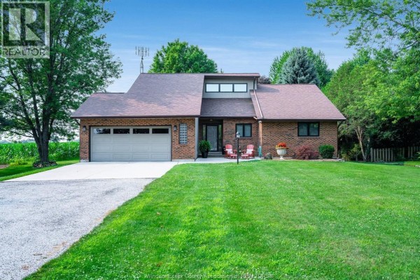 Living room with vaulted ceiling, fireplace, large windows, hardwood floors, and plush seating. - 621 County Rd 20, Kingsville