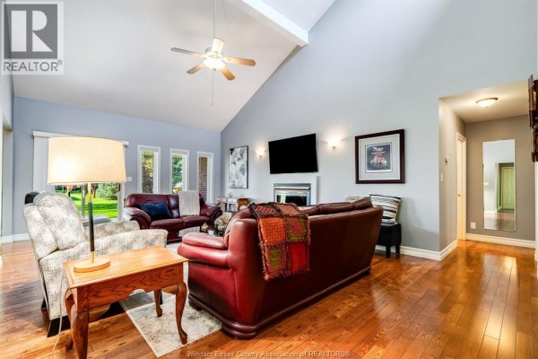 Living room with a gas fireplace, television, art, and leather furniture on hardwood floors. - 621 County Rd 20, Kingsville