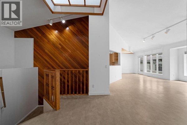 Spacious open-concept living area with white walls, high ceilings, and wooden built-in cabinetry. - 6210 53 Avenue, Camrose