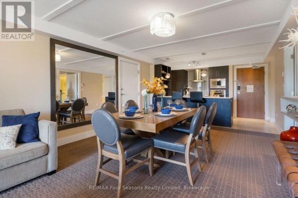 Living and dining area with plush carpet, large mirror reflecting kitchen, and seating. - 6210/6212 - 9 Harbour Street E, Collingwood