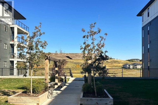 Courtyard with trees, a wooden pergola, and a view of rolling hills. - 6211, 15 Sage Meadows Landing Nw, Calgary