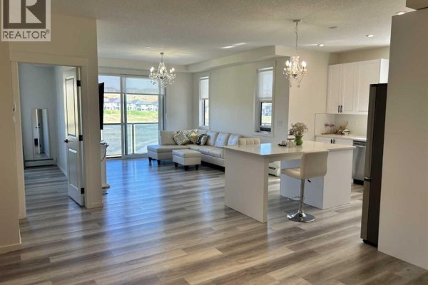 Open concept living room and kitchen with L-shaped sofa and island. - 6211, 15 Sage Meadows Landing Nw, Calgary