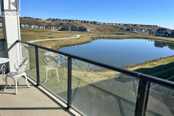 Balcony with a view of a pond and a suburban neighborhood. - 6211, 15 Sage Meadows Landing Nw, Calgary