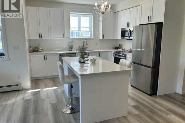 White kitchen with stainless steel appliances and a quartz-topped island. - 6211, 15 Sage Meadows Landing Nw, Calgary