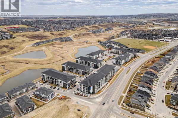 Aerial view of apartment buildings near ponds and a suburban landscape. - 6215, 15 Sage Meadows Landing Nw, Calgary