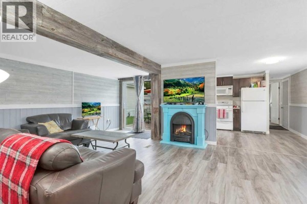 Living room with two brown leather sofas, a blue fireplace, and kitchen in background. - 6217 Galbraith Street, Red Deer