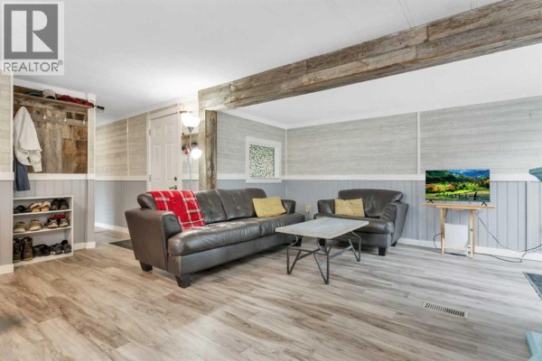 Living room from a different angle showing sofas, coffee table, and rustic wood beam. - 6217 Galbraith Street, Red Deer