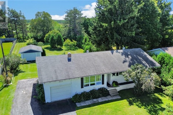 Aerial view of a white bungalow with a detached garage and surrounded by trees. - 6219 Highway 542, Mindemoya, Manitoulin Island