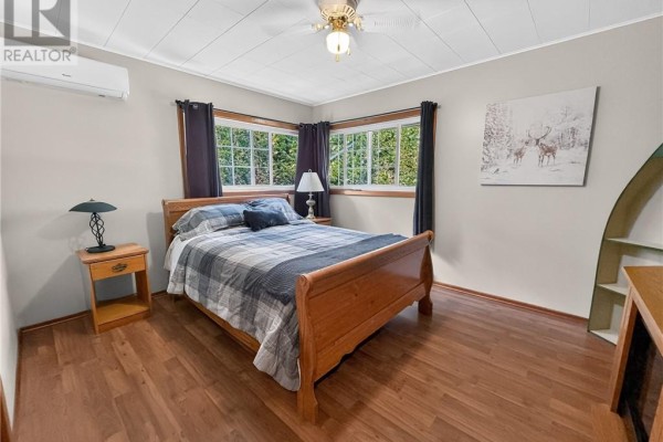 Bedroom with wood bed frame and plaid bedding, AC unit, and ceiling fan - 6219 Highway 542 Mindemoya, Manitoulin Island
