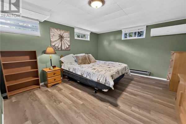 Bedroom with bed, nightstand, dresser, bookshelf, AC, and art - 6219 Highway 542 Mindemoya, Manitoulin Island