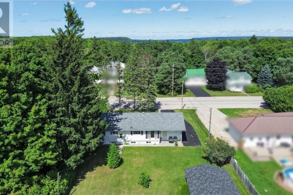 White house with grey roof, lawn, trees, and distant water - 6219 Highway 542 Mindemoya, Manitoulin Island