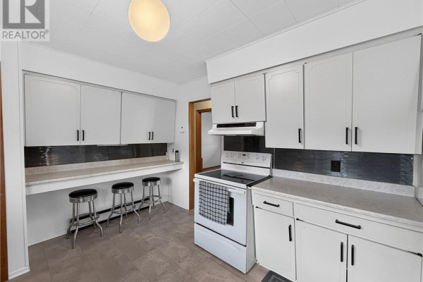 White cabinets, breakfast bar with stools, and tiled backsplash in kitchen - 6219 Highway 542 Mindemoya, Manitoulin Island