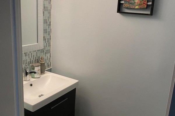 Powder room with a white sink, dark vanity, chrome faucet, and a decorative mirror. - 622 - 250 Manitoba Street, Toronto