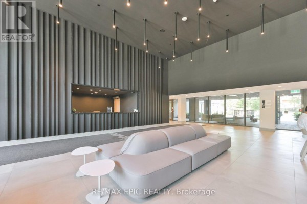 Modern lobby with a grey sofa, white side tables, and a textured dark grey wall. - 622 - 500 Wilson Avenue, Toronto