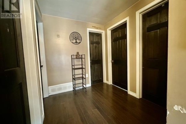Hallway with dark wood floors, tree of life decor, and dark doors - 622 Placid Ave Sault Ste Marie