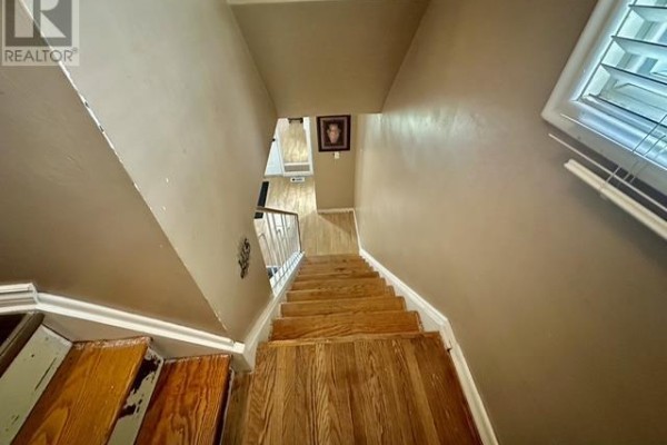 Wooden staircase with railing and picture on wall - 622 Placid Ave Sault Ste Marie