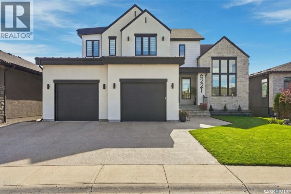 Modern two-story home exterior with beige stucco, stone accents, and a black roof. - 6221 Koep Avenue, Regina