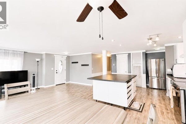 Open concept living area with light wood floors, a kitchen island, and stainless steel appliances. - 623 5 Avenue W, Hanna