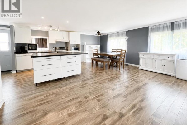 View of the kitchen, dining area with wooden table and chairs, and living room space. - 623 5 Avenue W, Hanna
