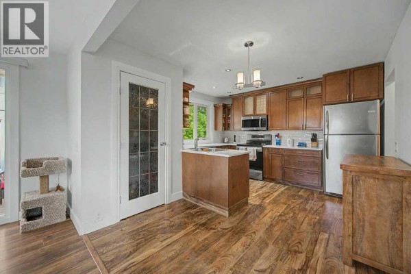 Kitchen with light gray walls, dark wood cabinets, stainless steel appliances, and a cat tree. - 623 Cantrell Place Sw, Calgary