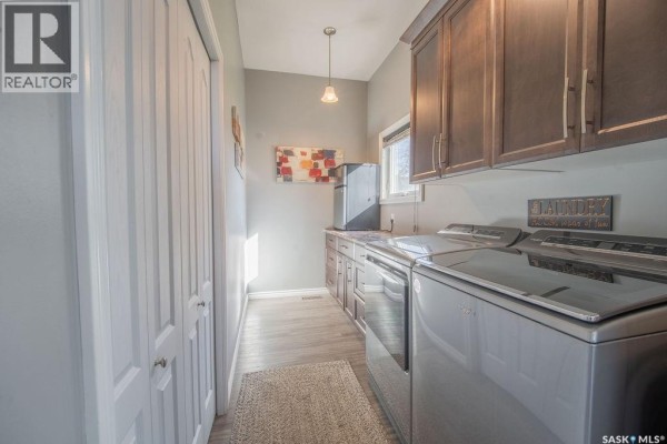 Laundry room with grey walls, dark wood cabinets, washer, dryer, and a window. - 624 10th Street, Humboldt