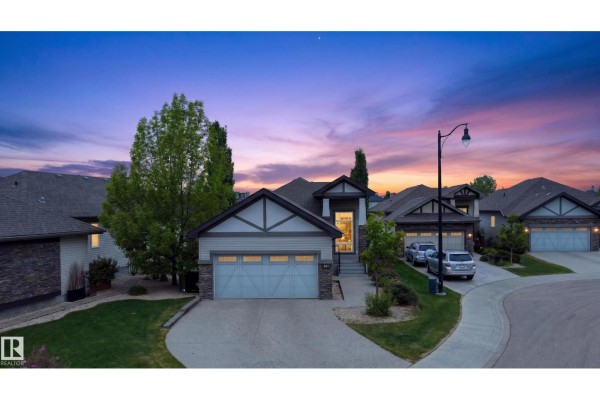 Exterior view of a suburban house with a two-car garage and landscaping during twilight. - 624 Cantor Ld Sw, Edmonton