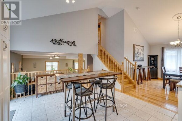 Open-concept living area with breakfast bar, dining set, and stairs - 624 Cedar Street W Shelburne