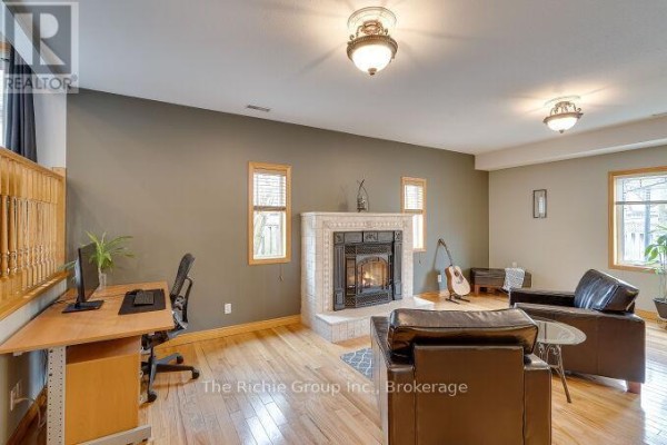 Living room with fireplace, desk, leather sofas, and guitar - 624 Cedar Street W Shelburne