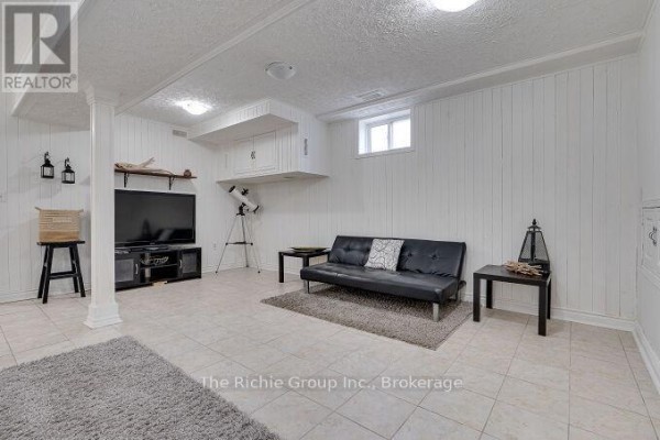 Black sofa, TV, and telescope in finished basement - 624 Cedar Street W Shelburne