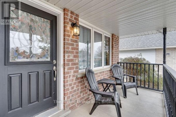L-shaped kitchen with white cabinets, stainless steel appliances, granite countertops, and ceramic tile flooring. - 624 Cedar Street W, Shelburne